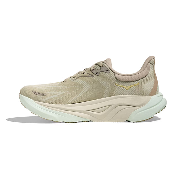 Hoka Arahi 8 dame løbesko i farven Oyster Mushroom/Truffle Salt har mesh-overdel, snørelukning og subtilt mønster. Den tykke lysegrønne og beige sål giver stabilitet. Skoen ses fra venstre side på hvid baggrund.