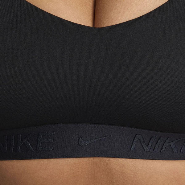 Nærbillede af en kvinde i Nike Padded Adjustable Sports Bra, Dame, Black/Black. Det synlige Nike-logo og Dri-FIT-teknologien giver komfort, støtte og stil - ideelt til træning.