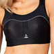 En kvinde er iført Purelime Compression Bra High Impact, Dame, i sort med grå syninger og tre små hvide ovaler på forsiden. Purelime-mærket står nederst på venstre side af denne high impact-bh.