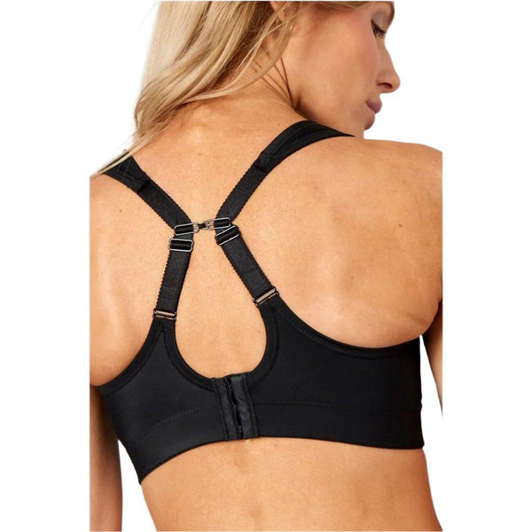 En kvinde med blondt hår ses bagfra iført Purelime Compression Bra High Impact til kvinder i sort med justerbare stropper og hægtelukning nederst på ryggen. Hun er drejet lidt til den ene side.