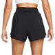 En kvinde ses bagfra iført en hvid crop top og Nike High-Waisted 3" 2in1 Shorts, Dame, Black. Hendes arme er afslappede ved siden af hende mod en almindelig hvid baggrund.