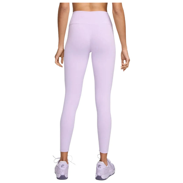 En person kigger væk fra kameraet iført Nike One High Waist 7/8 Tight-leggings til kvinder i lilla og hvide sportssko. Baggrunden er almindelig hvid.