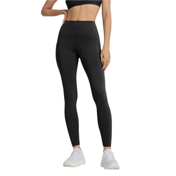 En person står model til New Balance Sleek Pocket High Rise Tights, Dame, Black med en sort sports-bh og hvide sportssko på en hvid baggrund. De højtaljede leggings har sidelommer. Personens ansigt er ikke synligt.