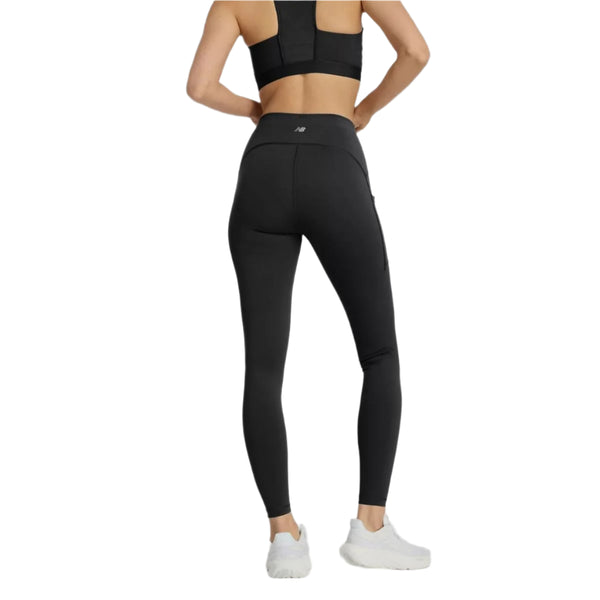 En person iført New Balance Sleek Pocket High Rise Tights, Dame, Black og en sort sports-bh står med ryggen til og viser bagsiden af tøjet. De har også hvide sportssko på mod en almindelig hvid baggrund.
