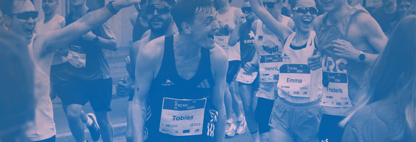 En gruppe maratonløbere iført startnumre, herunder en med navnet Tobias og en anden med navnet Emma, deltager i et løb og ser ud til at heppe og fejre.