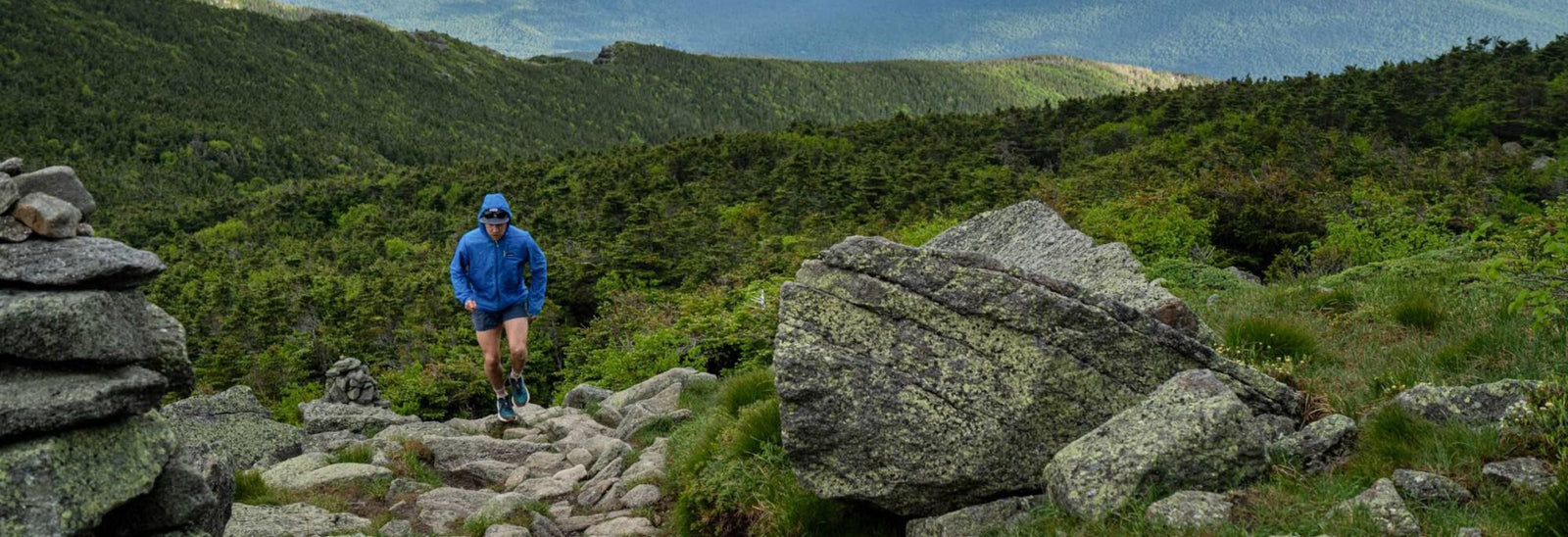 En person iført en grøn skjorte og en sort Patagonia-rygsæk ses bagfra. Personen har også et smartwatch på sit venstre håndled. Baggrunden er et abstrakt vægmaleri.