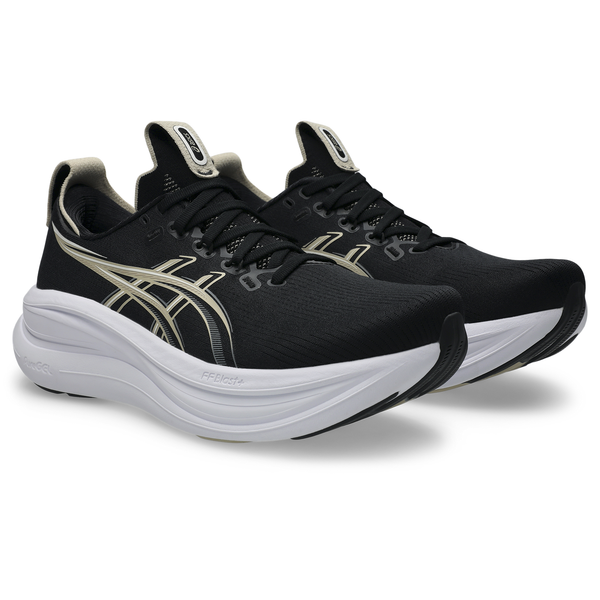 Et par ASICS Gel-Nimbus 28 til herre i farven Black/Feather Grey vises set fra en vinkel og fremstår med et elegant design med hvide såler og beige detaljer. Disse løbesko har snørelukning, synligt ASICS-logo på siden og tungen og er udviklet til maksimal stødabsorbering for at sikre optimal komfort.