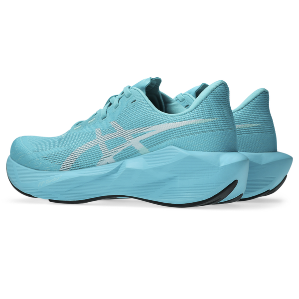 Et par Asics Novablast 6 Dame-løbesko i farvekombinationen Energy Aqua/White, med hvide detaljer og tykke, strukturerede såler, er placeret side om side med fronten vendt mod venstre, hvor den højre sko står lidt bag den venstre.
