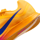 Et nærbillede af hælen og mellemsålen på Nike Zoom Rival Distance, Herre, Citron Pulse/Indigo Burst-Hyper Violet, viser en blå Swoosh, tekstureret mesh-overdel og orange-hvid sål på en almindelig hvid baggrund.