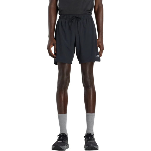 En mand står med front mod en sort t-shirt, New Balance Rc Lined Sh 7In løbeshorts for herre i sort med et lille logo, grå sokker og sorte sneakers på en almindelig hvid baggrund.