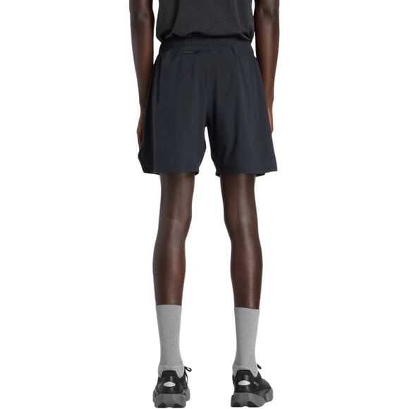 En person står med front mod kameraet iført en sort t-shirt, New Balance Rc Lined Sh 7In shorts til mænd i sort, grå strømper og sorte sneakers på en almindelig hvid baggrund.