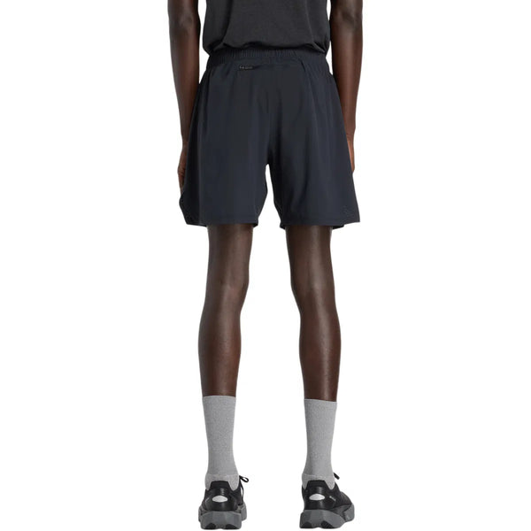 En person står med front mod kameraet iført en sort t-shirt, New Balance Rc Lined Sh 7In shorts til mænd i sort, grå strømper og sorte sneakers på en almindelig hvid baggrund.