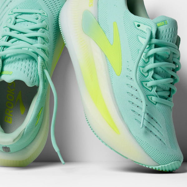 Nærbillede af Brooks Glycerin Max 2, Dame løbesko i Yucca/Nightlife/White, med overdel i mesh og hvid sål. Brooks-branding er synlig på indersiden af den ene sko mod en hvid baggrund. Designet til maksimal komfort.