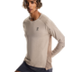 En person med krøllet hår bærer On Performance Long-T, Herre, Desert/Cinder med mørke shorts på en hvid baggrund - det hurtigtørrende materiale gør den perfekt til træning i køligere temperaturer.