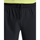 Nærbillede af en person iført On 5" Performance 2/1 Shorts, Herre, Black, lavet af åndbart materiale med løst bundne snore foran; vist fra taljen til midt på låret og sat sammen med en gul skjorte.