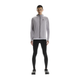 En person kigger fremad mod en hvid baggrund iført On Performance Tights, Herre, Black, sammen med en lysegrå jakke med hætte, sorte sportssko og en hvid skjorte indenunder.
