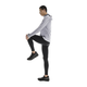 En person i sportstøj står på et ben og strækker sig mod en hvid baggrund iført On Performance Tights, Herre, Black, designet til optimal præstation.