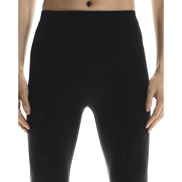 En person står med hænderne i siden iført On Performance Tights, Herre, Black. Billedet er beskåret fra midt på torsoen til lårene mod en hvid baggrund.