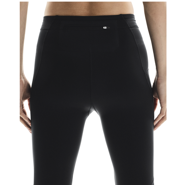 En mand ses fra taljen og ned, med ansigtet vendt væk, iført On Performance Tights, Herre, Black. Hans hænder hviler i siden, mens lyset fremhæver strømpebuksernes tekstur og pasform.
