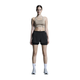En person står med ansigtet fremad i beige træningstøj - en sports-bh og On 3" Performance 2/1 Shorts til kvinder i sort - sammen med hvide sokker og lyse sneakers på en almindelig hvid baggrund.