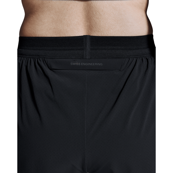 Nærbillede af en kvindes lænd i sorte On 3" Performance 2/1 Shorts. Den elastiske linning viser "SWISS ENGINEERING" over en skjult lomme, hvilket gør disse shorts til ideel træningstøj til løb dame og aktive sysler.