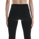 En person ses bagfra iført On Performance Tights Winter, Dame, Black, med synlige sømme og sidelommer. Armene hviler i siden mod en almindelig hvid baggrund, som fremhæver det slanke design.
