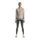 En kvinde ser frem for sig iført en On Weather Vest Dame i Desert/Eclipse over en lysegrå langærmet top, mørkegrå leggings og hvide sneakers - perfekt vejrbeskyttelse til løb - på en almindelig hvid baggrund.