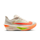 Et sidebillede af Nike Zoom Fly 6 Dame løbesko i Pale Ivory/Hyper Crimson med orange og grønne accenter, en tyk ZoomX-sål, en fremtrædende Swoosh på siden og en responsiv kulfiberplade, der giver høj ydeevne.