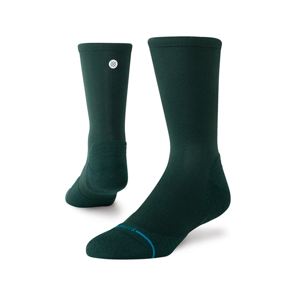 Stance Run Light Crew-strømperne, Unisex i Pine, har et mørkegrønt design med et lille hvidt cirkulært logo i toppen, der er udviklet til optimal åndbarhed og vist på en hvid baggrund.