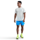En mand i en hvid Nike Stride Running Short-Sleeve Top og blå shorts.
