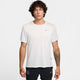 En mand med krøllet hår er iført en hvid Nike Miler kortærmet løbetop, Herre (Summit White/Reflective Silver) og sorte Nike shorts. Han står med ansigtet fremad mod en almindelig hvid baggrund med et neutralt udtryk.