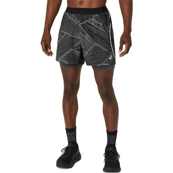 En person er iført Asics Limited Series Lite-Show Short, Herre, Performance Black. Kun underkroppen og benene er synlige mod en almindelig hvid baggrund. De har også sorte sokker og sorte sneakers på.