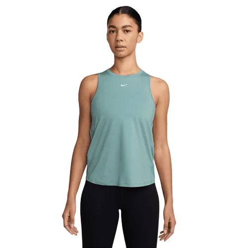 En kvinde står med ansigtet fremad iført en Nike Dri-FIT Classic Tank Top i Cannon/White og sorte leggings på en almindelig hvid baggrund.