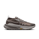 Nike Zegama 2 til mænd i Ironstone/Cave Stone-College Grey har en lav profil, perforeret overdel, tyk sål og synligt "ZOOMX"-branding - ideel til tekniske stier. Vises mod en almindelig hvid baggrund.