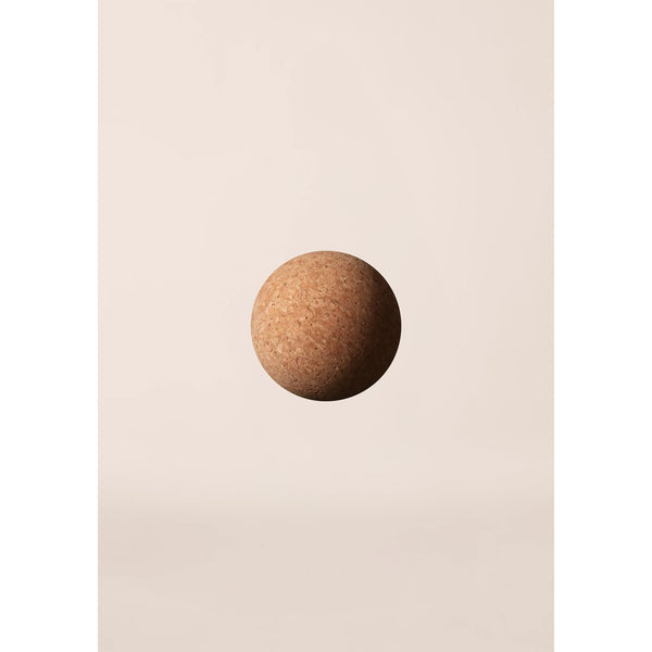 En Casall Pressure Point Ball i naturkork hænger i luften mod en almindelig, lys beige baggrund. Det minimalistiske billede har blød belysning og ingen andre objekter.
