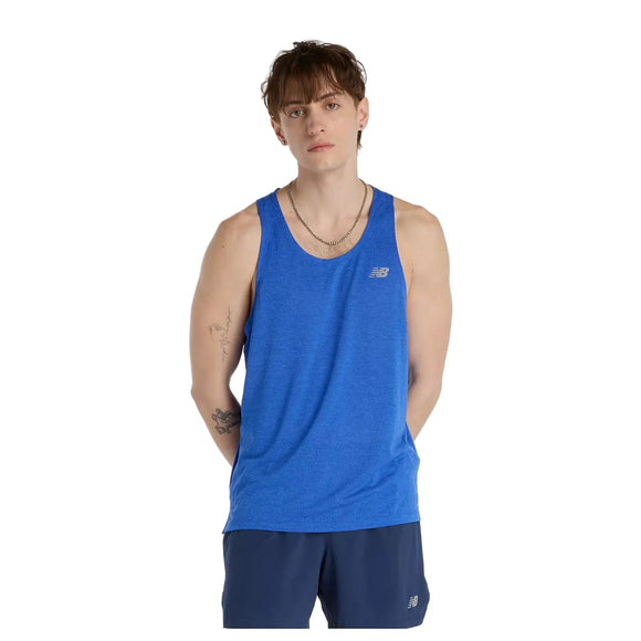 En person med kort brunt hår står model til New Balance Athletics Tank, Herre, Blue Gemstone Heather, sammen med marineblå shorts på en almindelig hvid baggrund - og viser et klassisk træningssæt herre-look.
