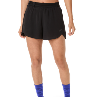 En person iført ASICS Metarun Split Shorts til kvinder i Performance Black og lyseblå sokker står på en almindelig hvid baggrund, hvor kun underkroppen og benene er synlige.