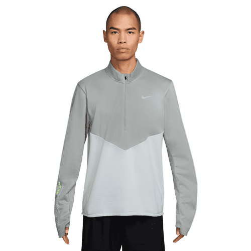 En mand kigger fremad i en lysegrå Nike Pacer Winterized 1/2-Zip Running Top (Pure Platinum/Reflective Silver) med et lille logo på venstre bryst og Dri-FIT-teknologi sammen med sorte shorts. Baggrunden er almindelig hvid.