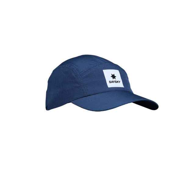 Saysky Flow Cap er en blå unisex-løbekasket med en let buet skygge og et hvidt mærke med en sort stjerne og et fedt SAYSKY-logo. Denne åndbare løbecap er vist mod en almindelig hvid baggrund.