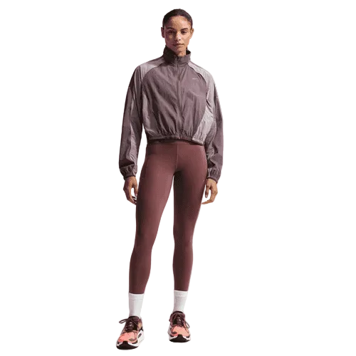 En kvinde iført en Nike Swift Repel UV Protection løbejakke i Tattoo/LT Violet Ore/Reflective Silver og tights.