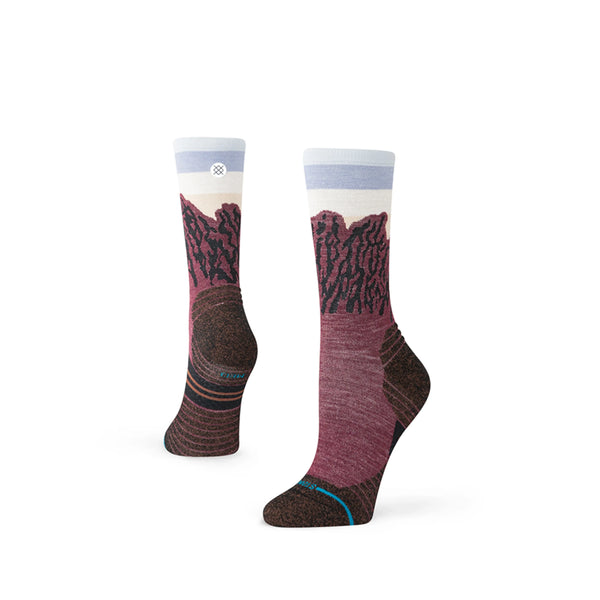 Stance The Ridge Light Wool Crew, Dame, Wine-strømperne har en rødbrun og brun bund med et bjerglandskab i lilla, rødbrune og lyseblå toner samt et lille cirkulært logo nær manchetten.