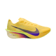 En Nike Vaporfly Next% 4 damesko i Citron Pulse/Indigo Burst-Laser Orange vises på en hvid baggrund med gul overdel, lilla swoosh, gradient lilla/lyserød mellemsål og lysegrøn ydersål.