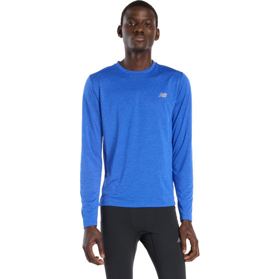 En person iført New Balance Athletics Long Sleeve, Herre, Blue Gemstone Heather og sorte atletiske leggings står med front mod en almindelig hvid baggrund.