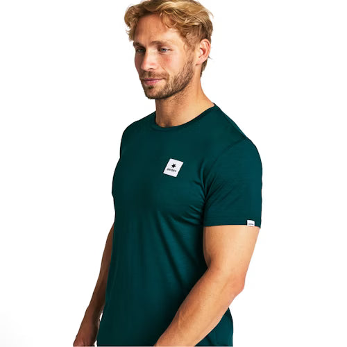 En mand med lysebrunt hår og skæg er iført Saysky Statement Pace T-Shirt, Herre, Green med fugttransporterende stof og et lille hvidt rektangulært logo på brystet og ærmet. Han står let drejet til højre mod en hvid baggrund.