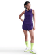 En kvinde med hånden på hoften bærer en ærmeløs Nike AeroSwift Running Singlet Dame i Court Purple/White med matchende shorts, neongrønne knæstrømper og hvide sportssko, der fremhæver Dri-FIT ADV-teknologi, mens hun kigger lidt til venstre.