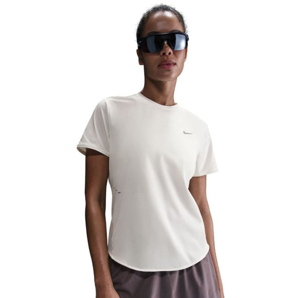 Med front mod en hvid baggrund er en person iført Nike Swift SS Running Top (Dame, Sail/Reflective Silver), store sorte solbriller og lilla shorts.