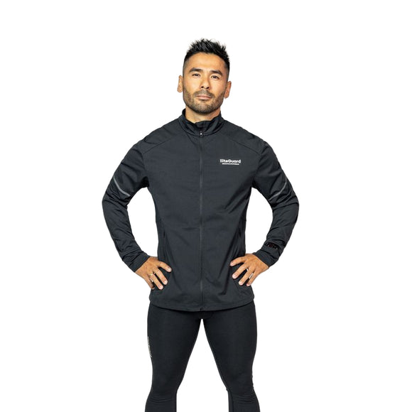 En mand står på en almindelig hvid baggrund iført den sorte LiiteGuard Hydro-Tech løbejakke til mænd med et lille logo på venstre bryst og sorte leggings. Hans hænder hviler på hofterne, mens han ser direkte ind i kameraet.