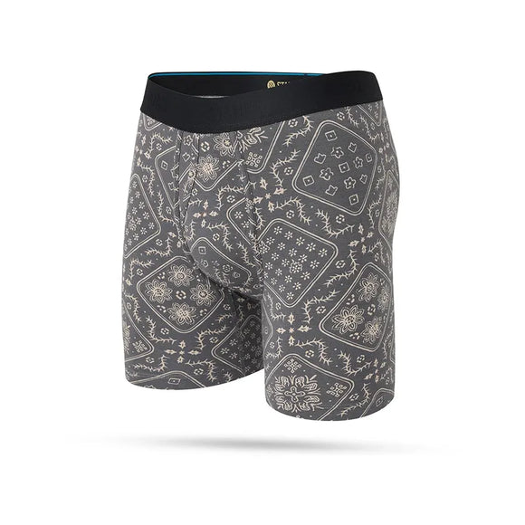 Stance It Is Paisley Wholester herre boxershorts i Stringgrey har en sort linning og et heldækkende gråt og beige Paisley-bandana-mønster, fremstillet i fugttransporterende stof for komfort hele dagen. Vist på en almindelig hvid baggrund.