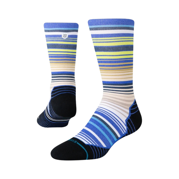 Et par Stance Jorongo Light Crew unisex-sokker i blå med vandrette striber i blå, marineblå, gul, beige og hvid. Sokkerne er fremstillet af slidstærke materialer, der sikrer god komfort, og har sorte tå-, hæl- og såldele samt Stance-logoet tæt på toppen. Jorongo Light Crew-sokkerne vises side om side på en hvid baggrund.