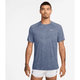 En person med kort hår og synlige tatoveringer på armene er iført en Nike Dri-FIT ADV kortærmet løbetop, Herre, i World Indigo/Htr/Reflective Silv med et lille logo på brystet og hvide shorts. Baggrunden er almindelig hvid.